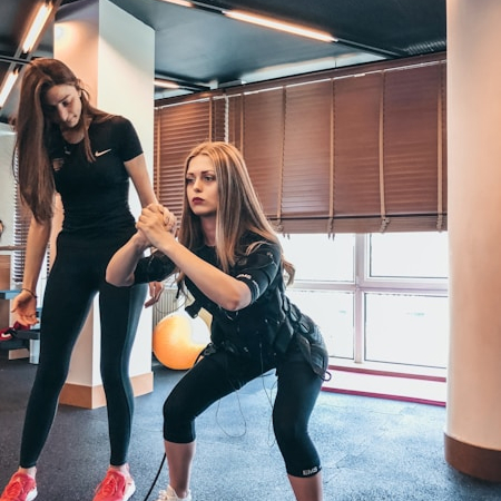 Two women engaging in fascia fitness exercises in a studio, improving flexibility, mobility, and connective tissue health.