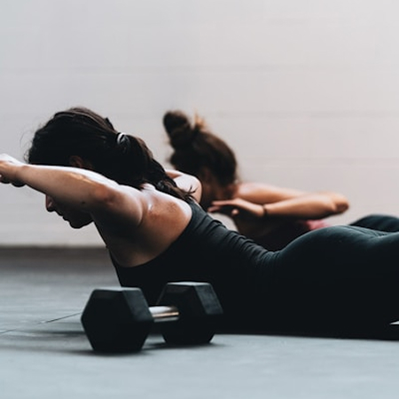 Certified personal trainer guiding a client through strength training exercises at a modern gym, focusing on strength and balance.
